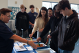 a group of students hold different colored sticks into silver pans