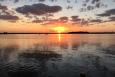 an orange sun sets over calm water 