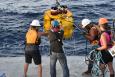 a crew on a boat helps retrieve a piece of equipment out of the water 