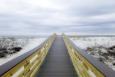 boardwalk leading out to a white beach under grey cloudy sky 