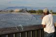 A recreational angler tosses a net out off a fishing pier.