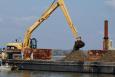 heavy machinery on a barge digging into piles of oyster cultch.