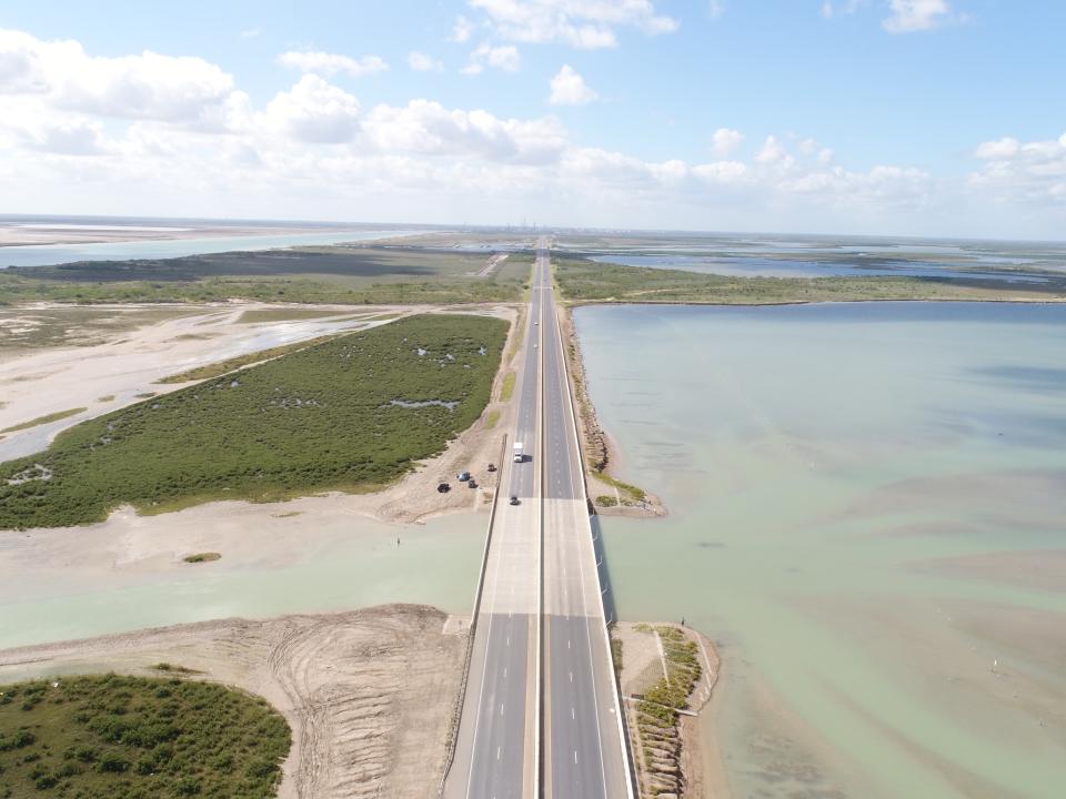 an aerial of a two lane road is shown with water on either side 