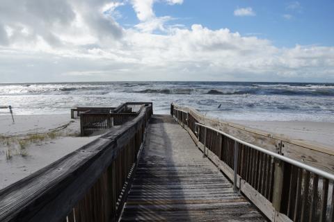 boardwalk leads down to a beach with crashing waves. 