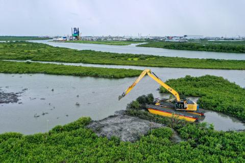 Aerial view of wetlands and marsh with a large excavator working among the landscape.