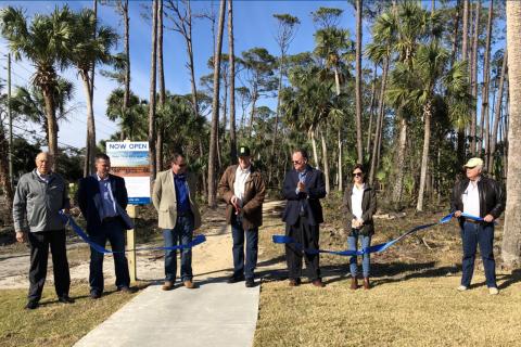 Agency officials and partners cut a ribbon to commemorate a project completion.