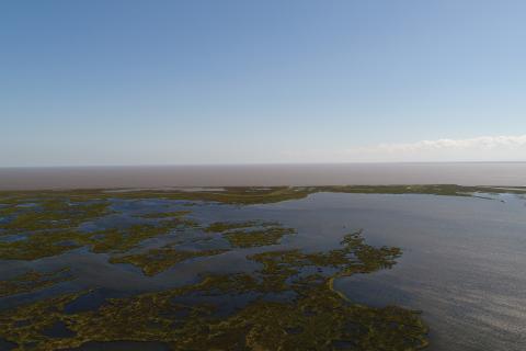 Aerial view of the Golden Triangle marsh restoration area. Green marsh is surrounded by open water in the Gulf of Mexico.