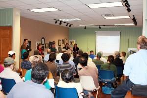 A room full of seated people watches a presentation