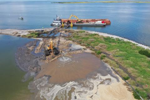 Equipment delivers sand onto a sliver of an island in the Gulf of Mexico.